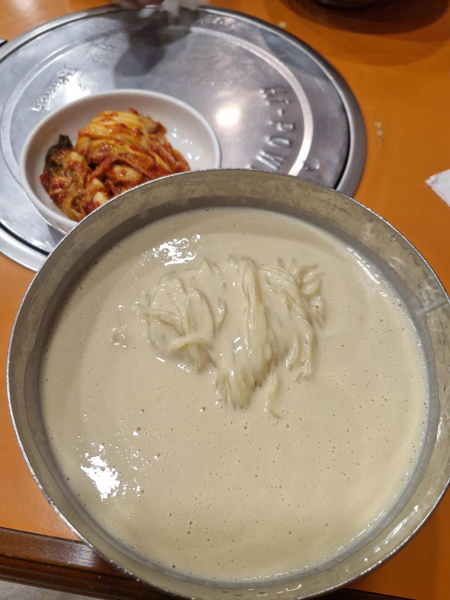 A big saucer is full of a cream-colored substance and doused noodles.