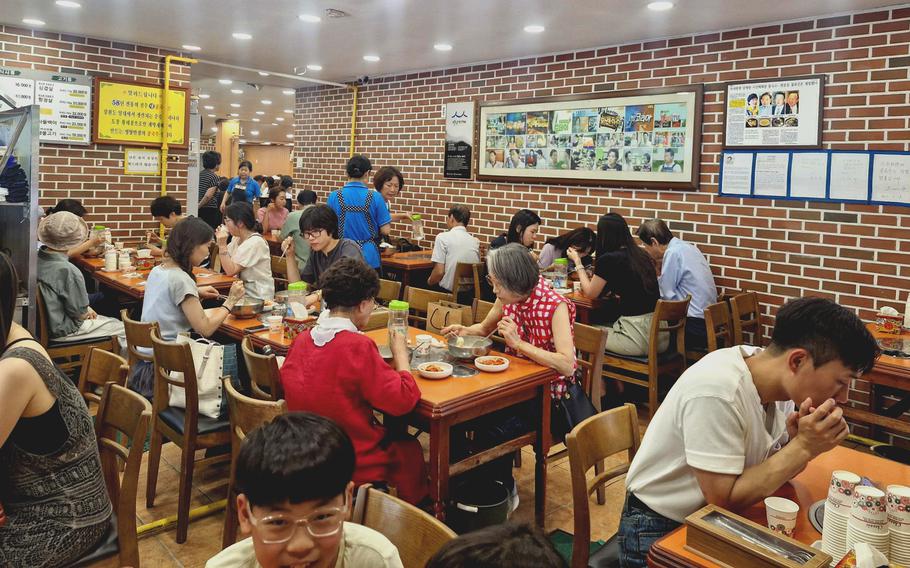 All the tables are occupied with people at a brick-walled one-room restaurant.