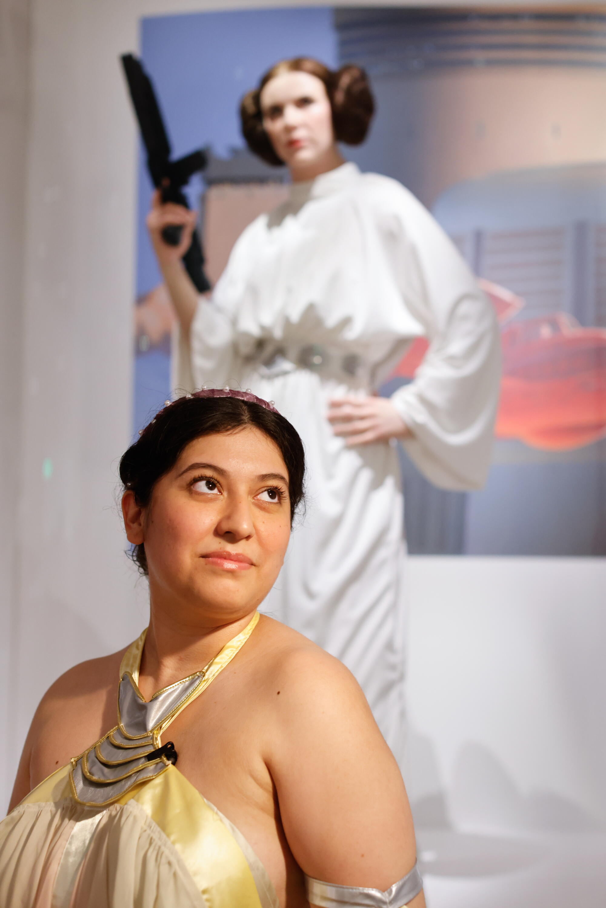 A woman dressed as Padmé Amidala in front of a statue of Princess Leia.