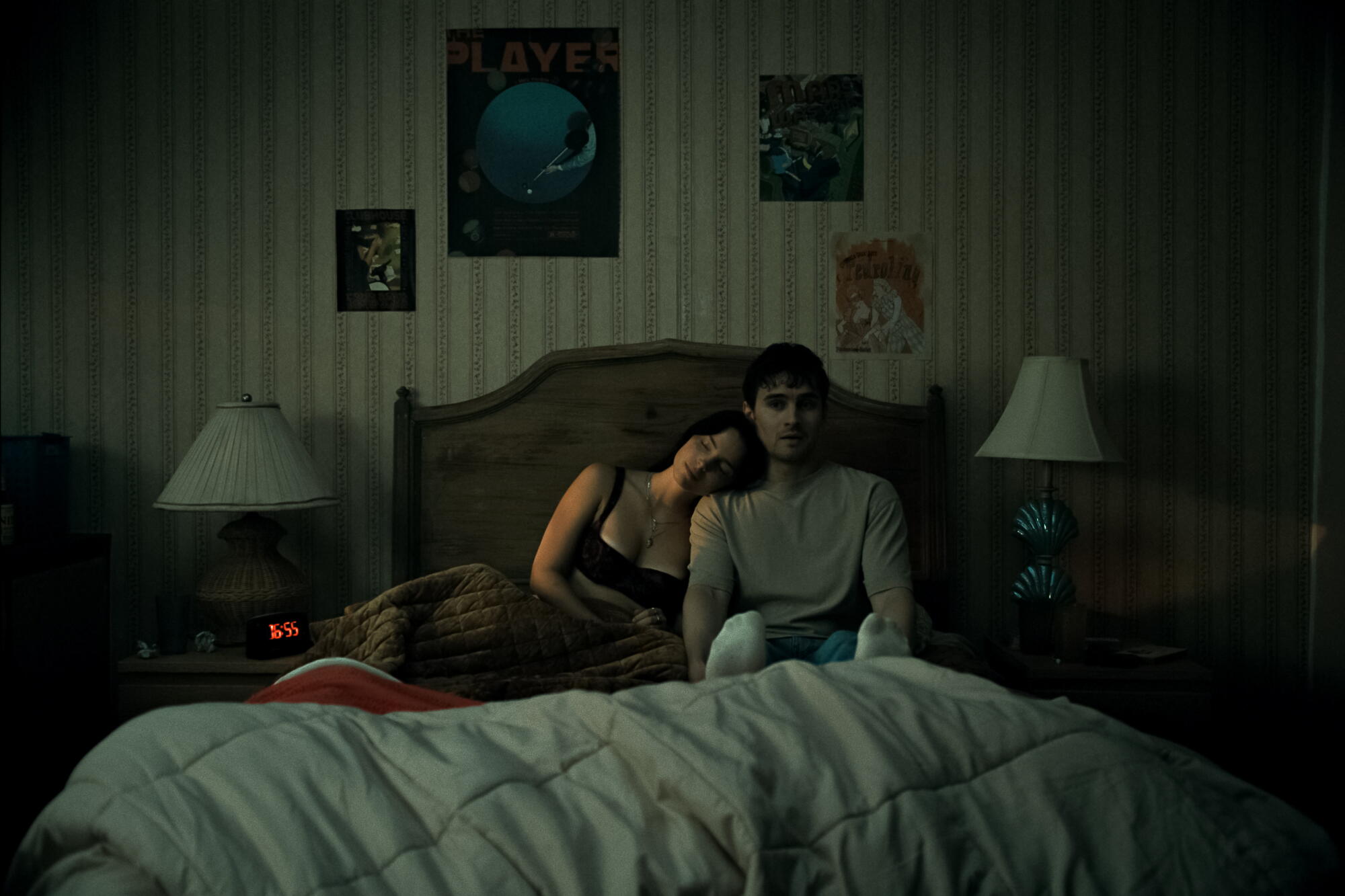 Two people stay awake in a bed together.