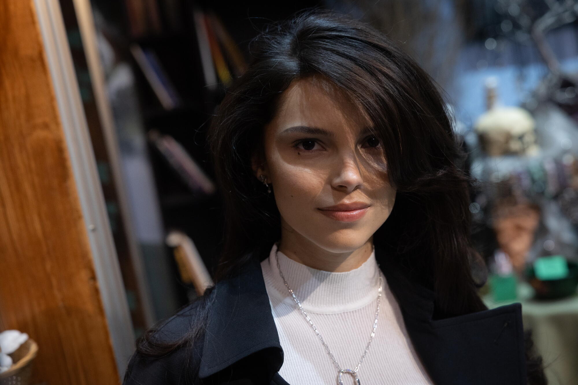 American actress Inde Navarette smiles slightly in a white shirt and black jacket