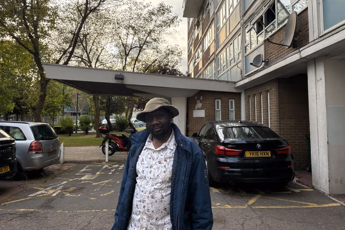 Pictured is Moses Onek outside the block where he lives with his family while waiting to be relocated by Brent Council 