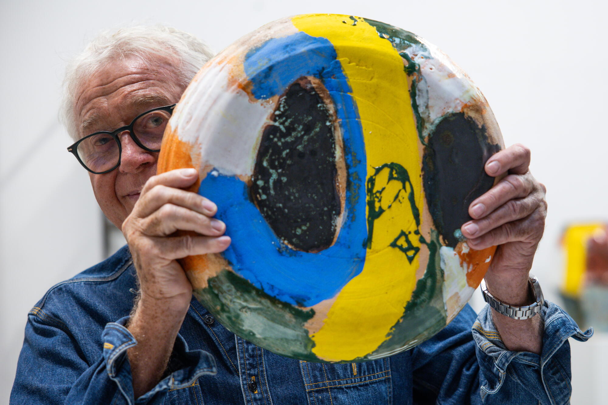 Roger Herman holds a colorful ceramic piece.