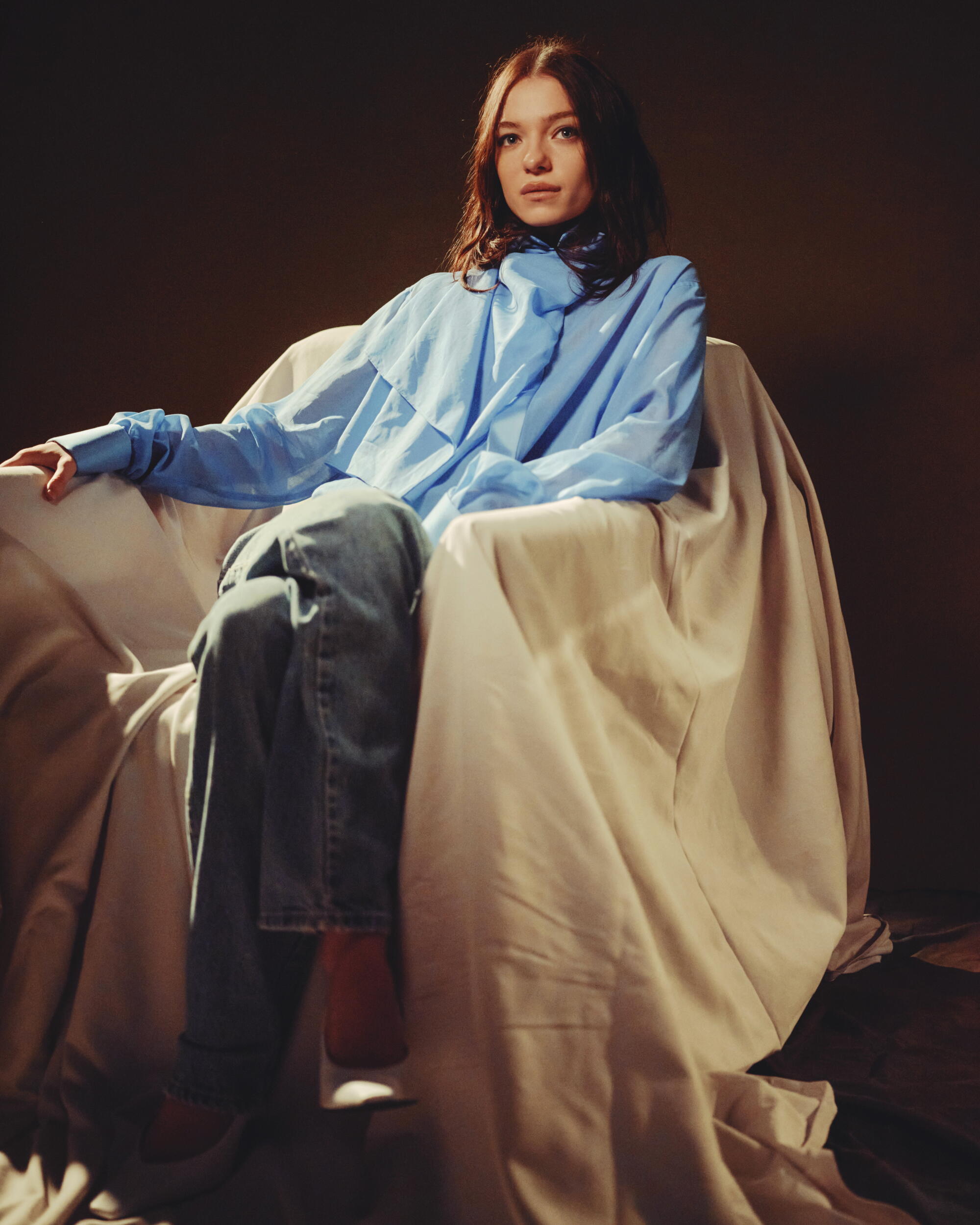 A woman sits in a cloth-swaddled chair.