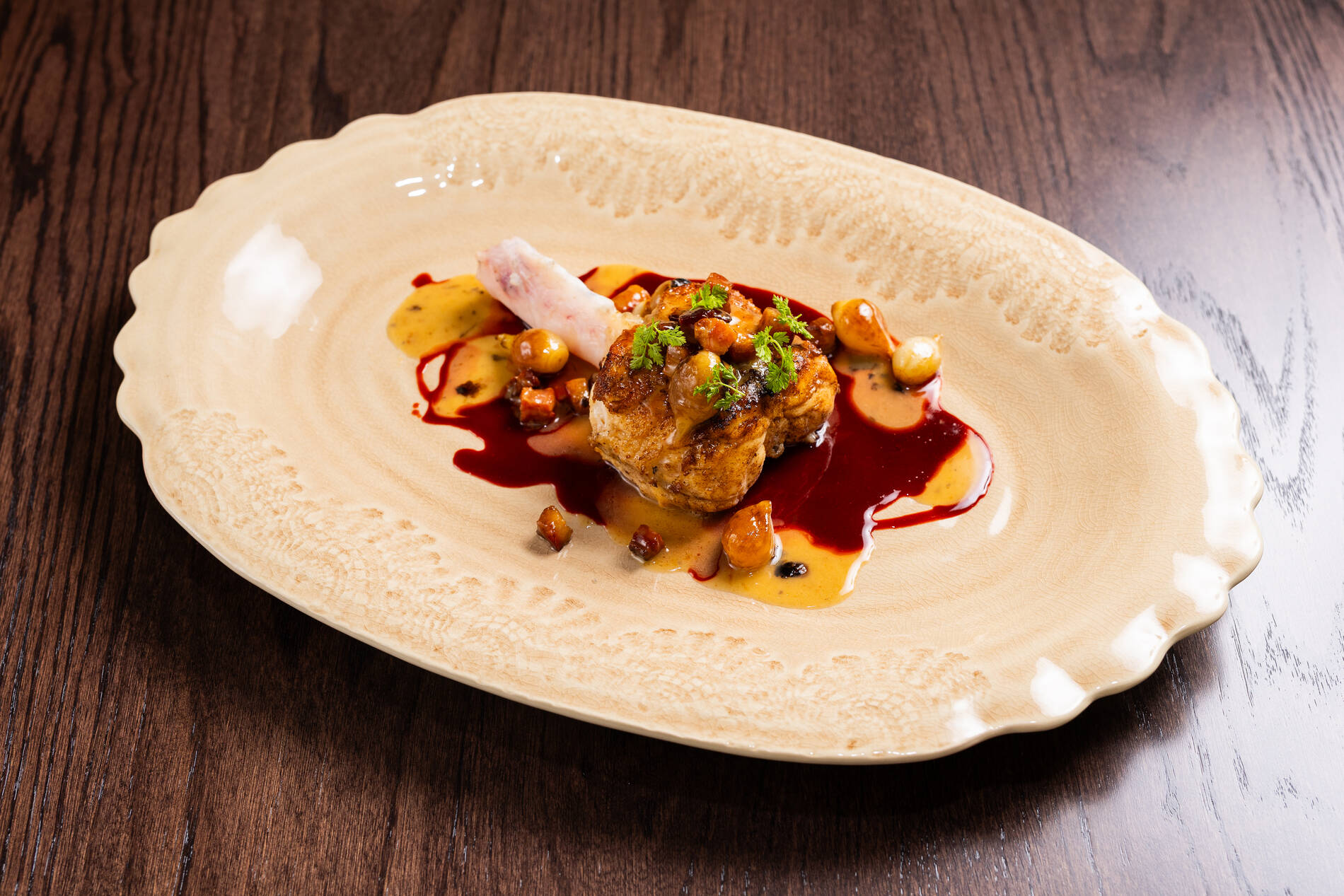 A gourmet dish featuring chicken, sauce, and garnishes on a decorative plate.